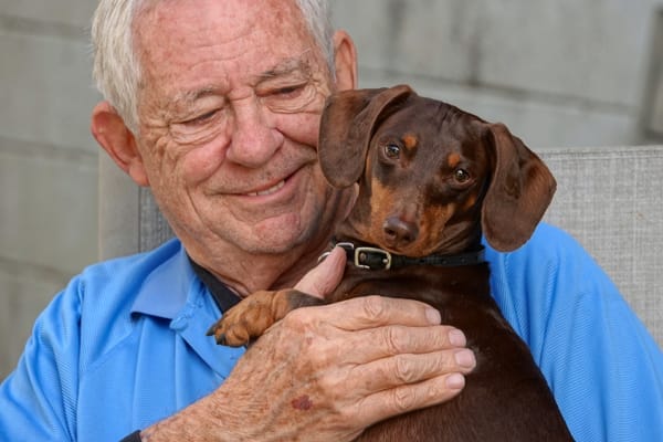 Happy, smiling senior man holding his dog