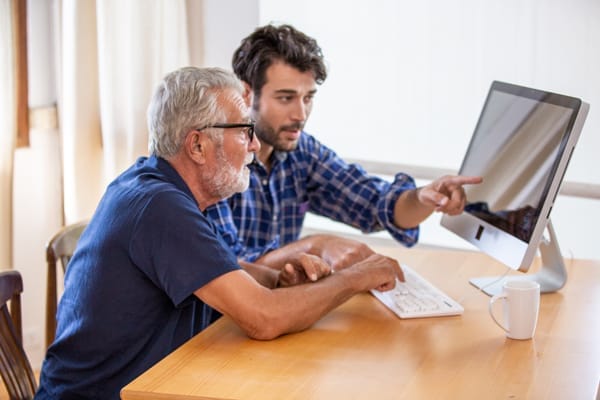 man teaching elderly man to using computer