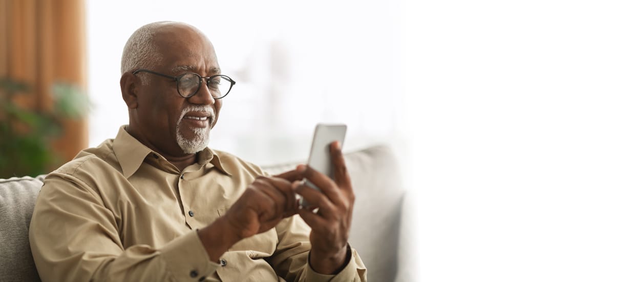 Senior Man On Smartphone Using Application At Home